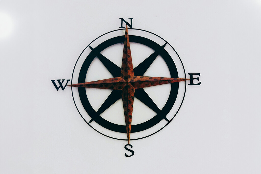Een decoratieve kompasroos met aanwijzingen (N, S, E, W) weergegeven op een witte achtergrond, die de verschillende fasen van een klantreis symboliseert.
