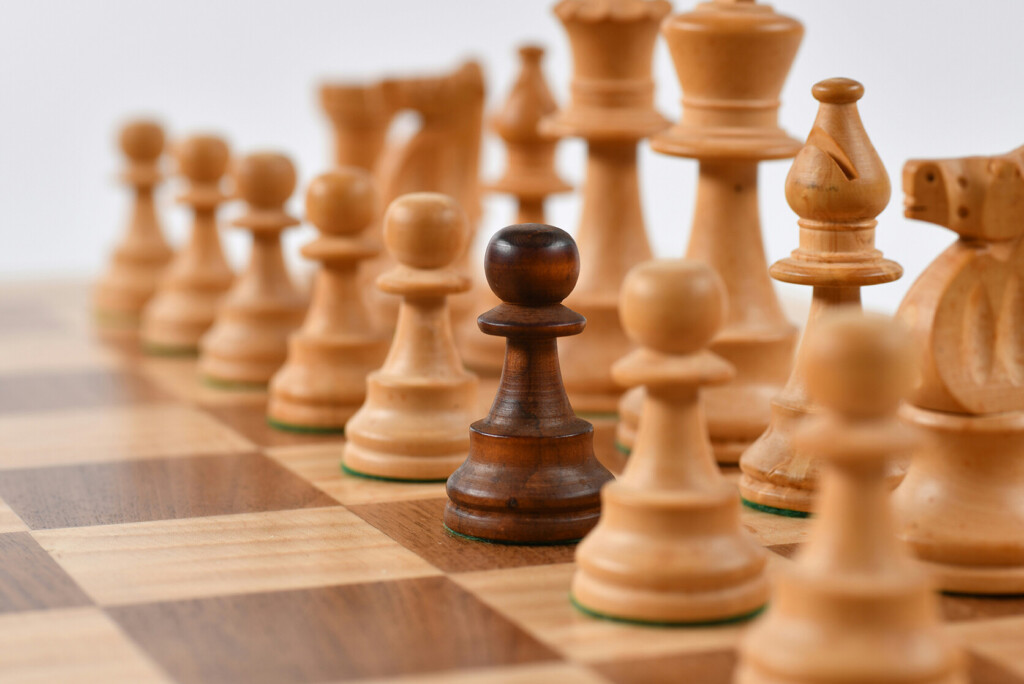 Close-up van een schaakbord met een zwarte pion die opvalt tussen de witte stukken op de eerste rij, wat de unieke verkoopargumenten ervan benadrukt.