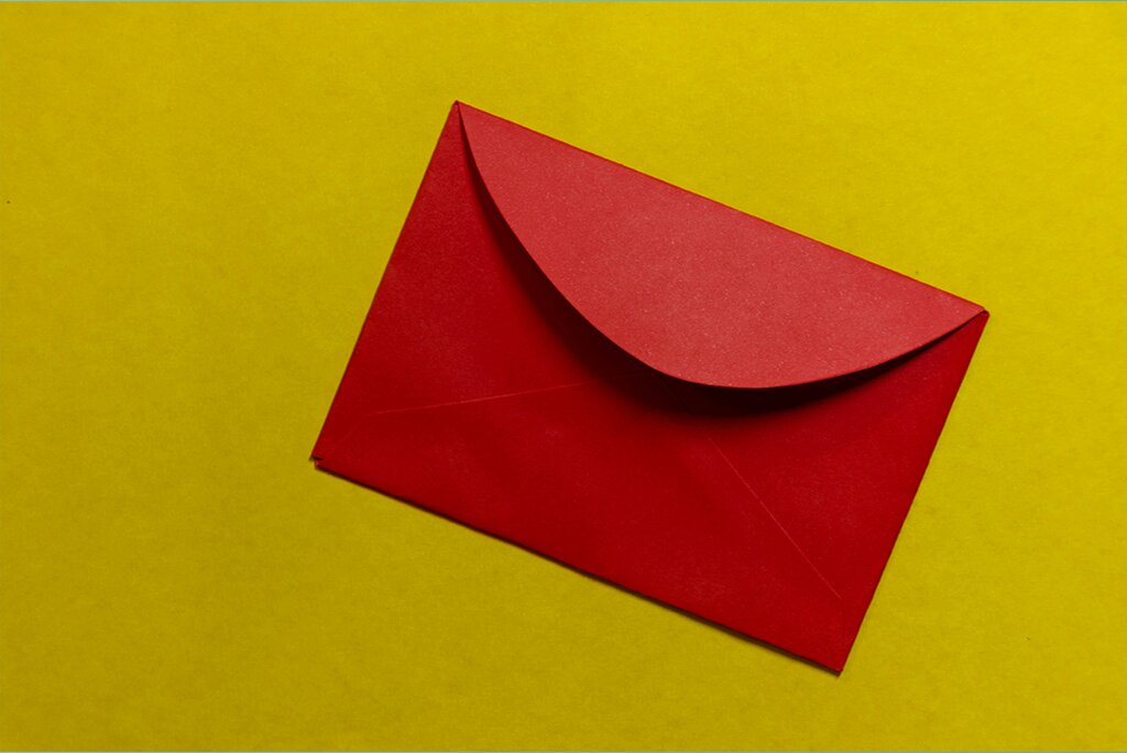 Een rode envelop, die een sleutelelement van koude acquisitietips symboliseert, wordt op een levendige gele achtergrond geplaatst.