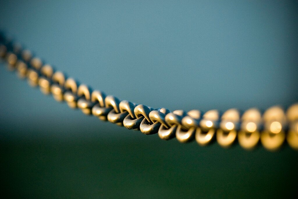 Een close-up van een metalen ketting tegen een groene en blauwe onscherpe achtergrond, die de ingewikkelde verbindingen in de kosten van linkbuilding-strategieën symboliseert.