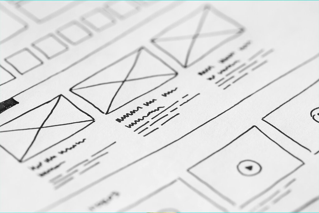 Een close-up van een wireframe-schets voor de lay-out van een webpagina, vakkundig gemaakt om de principes van UX-ontwerp te benadrukken, met vakken die afbeeldingen en tekstblokken vertegenwoordigen.