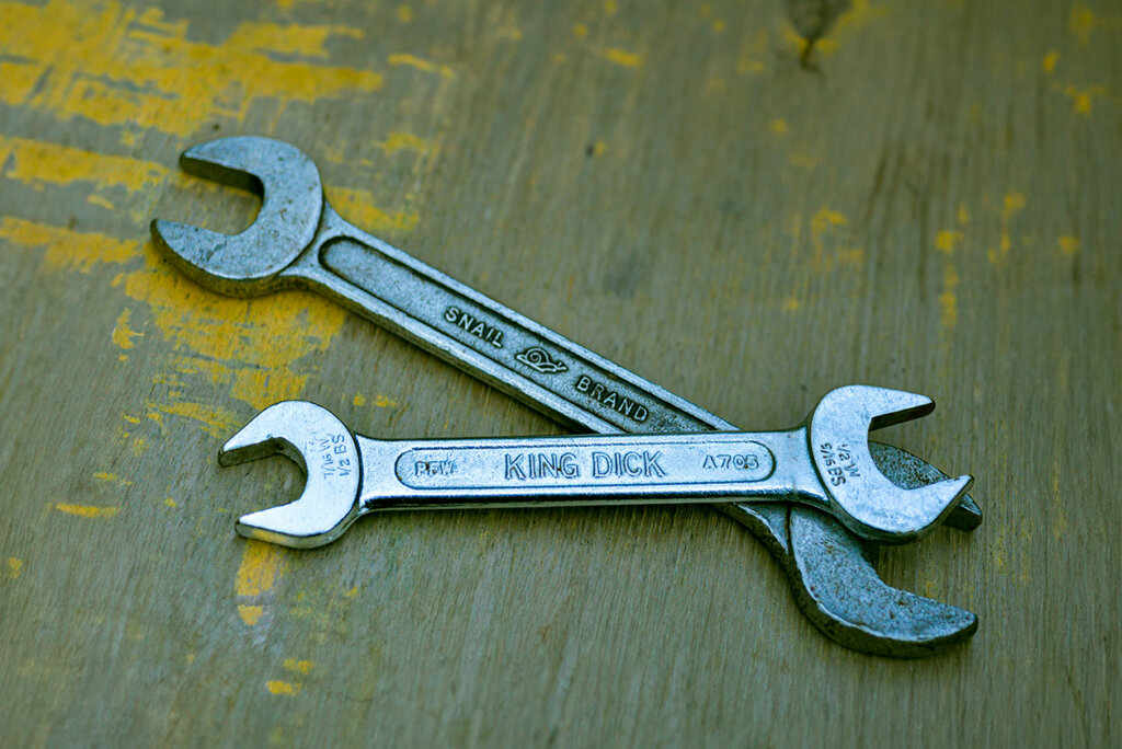 Twee metalen sleutels kruisen elkaar op een versleten houten oppervlak, wat het belang van regelmatige onderhoudskosten aantoont.