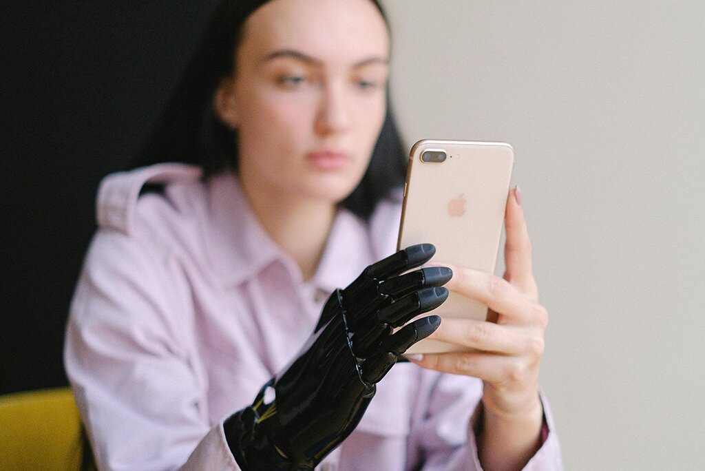 Een persoon met een prothetische hand houdt een smartphone vast en kijkt naar het scherm terwijl hij vooruitblikt op de innovaties van EEA 2025.